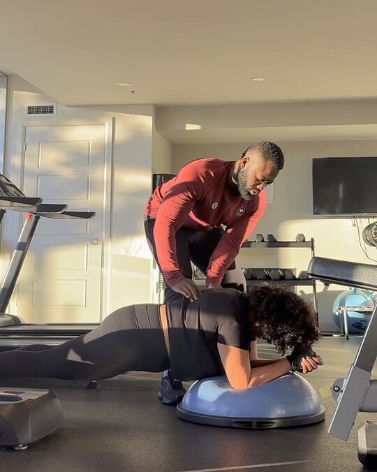 Doug cueing a client through a plank, his hands on her back.